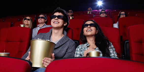 Funny people are watching a movie in 3D glasses in cinema